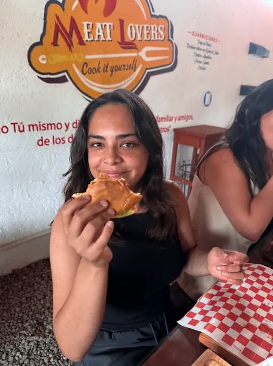 Comensal disfrutando una hamburguesa en Meat Lovers